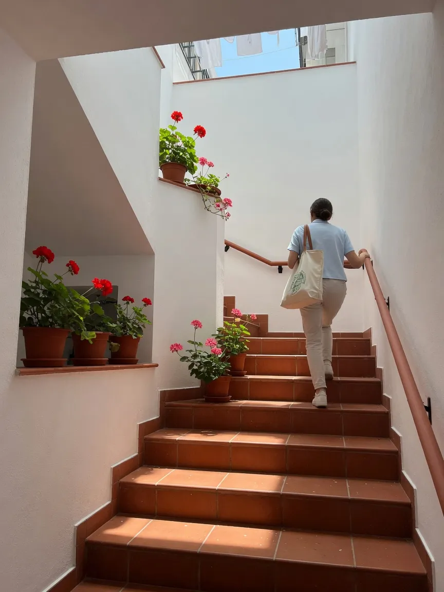 Llegada a domicilio en Granada: una persona de espaldas sube la escalera de baldosa con la bolsa del material.